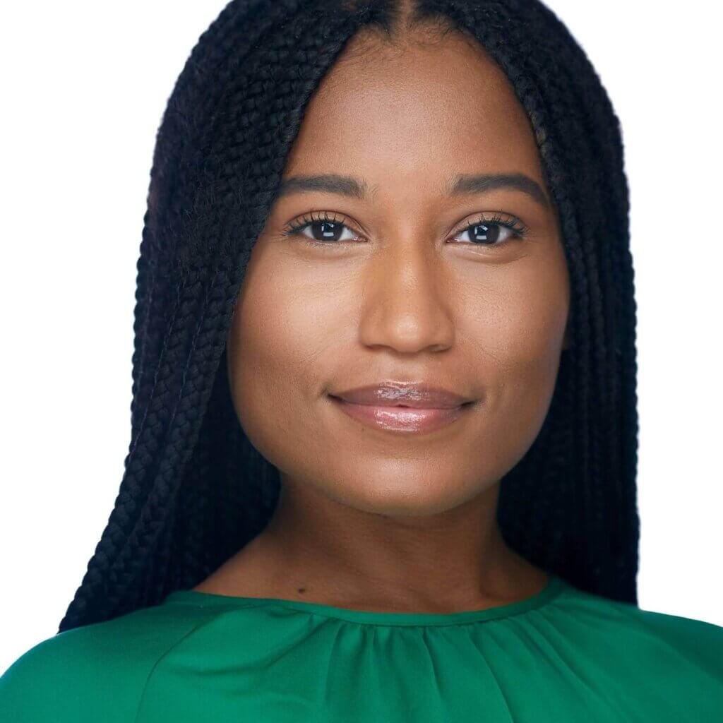 Portrait of an African American woman with long, braided hair, wearing a green top. Her headshot captures a calm and confident expression with a subtle smile. The plain white background accentuates their striking features and attire.