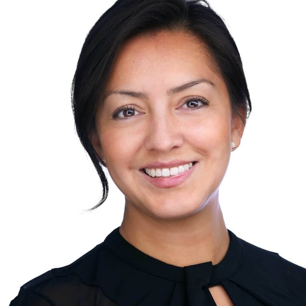 Headshot of a smiling Latina with short black hair, dressed in a black top, against a white background.